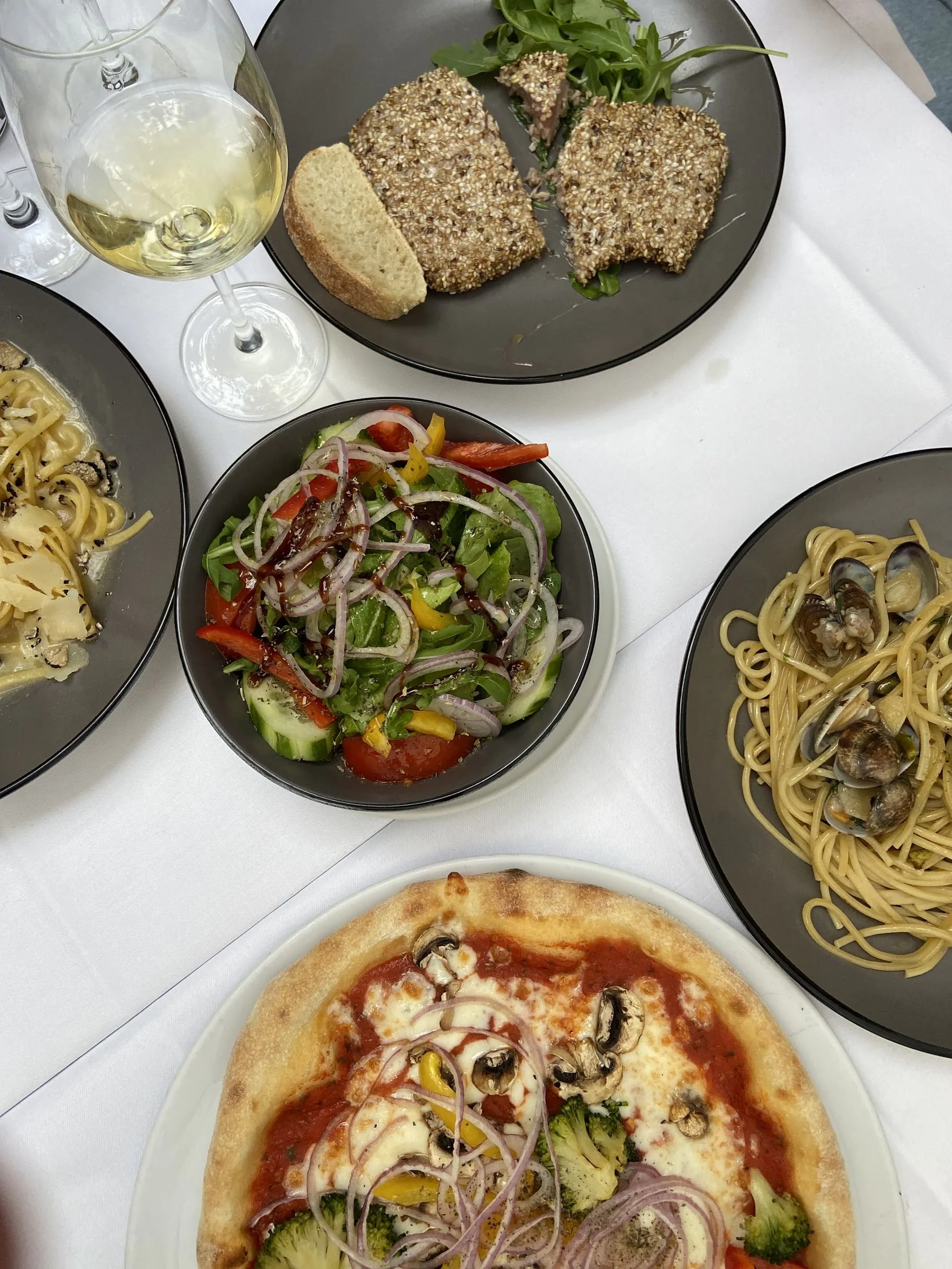 Gedeckte Tafel mit Pizza, Pasta und Wein